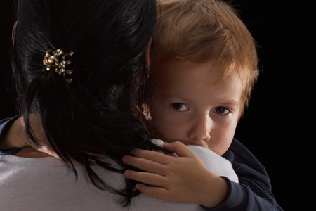 Adoption concept, an orphan is a little boy and his new mother. Happy childhood, caring for children. Sad boy on black backgroundの写真素材