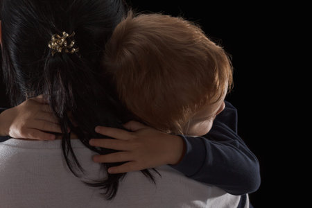 Adoption concept, an orphan is a little boy and his new mother. Happy childhood, caring for children. Sad boy on black backgroundの写真素材