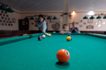 Woman playing in american pool billiard on green table.