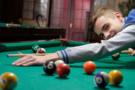 Teen playing in american pool billiard on green table happy funny hobby.の写真素材