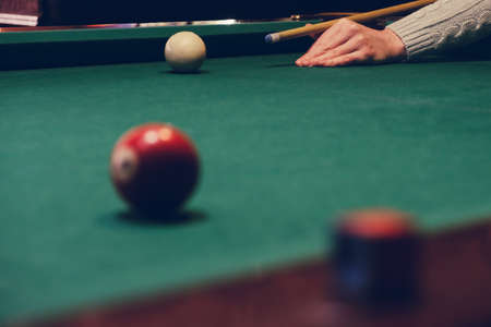 Hand holding billiard stick cue on a pool table ready to shot the ballの写真素材