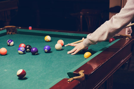 Hand holding billiard stick cue on a pool table ready to shot the ball