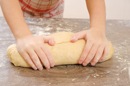 Unleavened dough for tortillas with flour and hand on kitchen table. Cooking burrito. Raw burritos