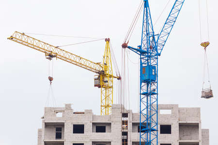 Building crane and building under construction against blue skyの写真素材