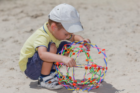 Beautiful boy play with ball on a sand beach outdoors