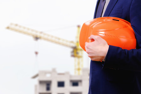 Concept, businessman builder with a helmet, looking construction city site with cranes