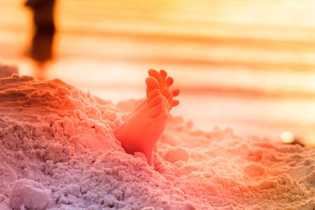 Beautiful boy play with shovel on a sand beach outdoorsの写真素材