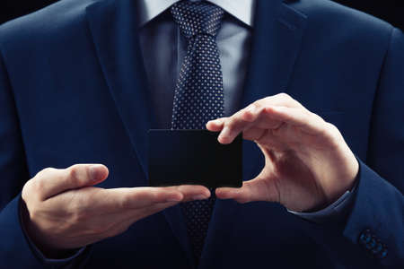 businessman showing empty card on black backgroundの写真素材