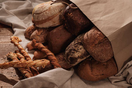 Fresh fragrant bread on the table. Food concept Wheat pastry in a paper bagの写真素材