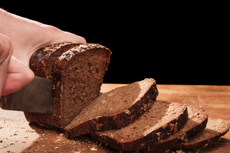 Chef cuts with a knife Whole Fresh fragrant bread on the table. Food concept Wheat pastry on cutting...