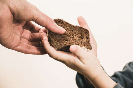 Two beggar hands palms up with cheap dirty bread. Poor children and people donations Volunteers Concept.の写真素材