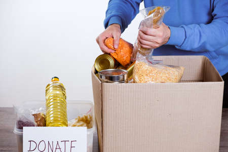 Food in a donation cardboard box, isolated on white background, volunteer fills the box.の写真素材
