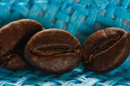 Set of fresh roasted macro coffee beans on blue wicker basket background.の写真素材