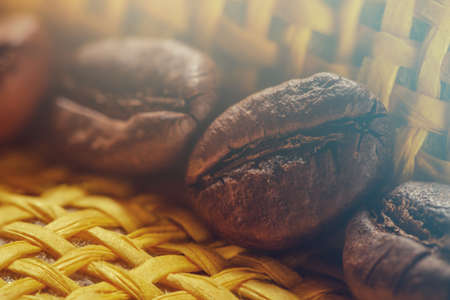 Set of fresh roasted macro coffee beans on yellow wicker basket background.の写真素材