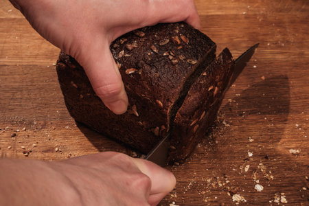 Chef cuts with a knife Whole Fresh fragrant bread on the table. Food concept Wheat pastry on cutting...