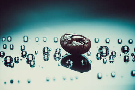 shiny fresh roasted coffee macro beans on glass dark background with water drops close upの写真素材