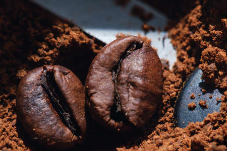 Electric coffee grinder with roasted coffee beans inside and coffee grains close-up view of the topの写真素材