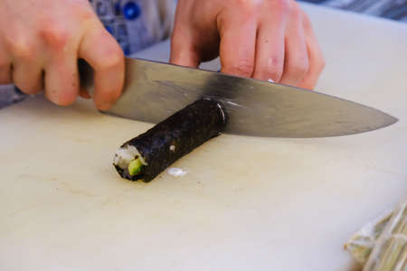 Sushi roll making preparation, close up on chef hands with a knifeの写真素材