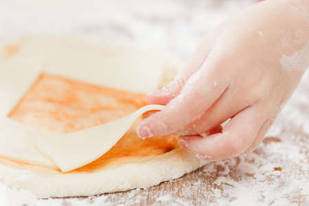 Cook putting salami over mozzarella and tomato on a raw pizza close-upの写真素材