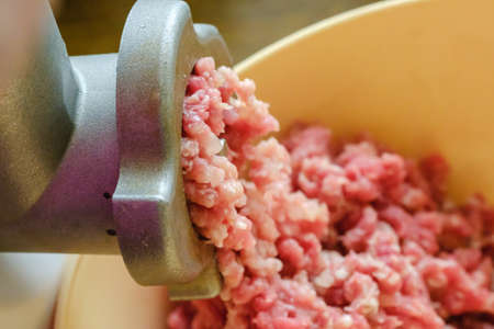 Close up of front part meat grinder or mincing-machine with mincemeat in. Showing the forcemeat process.の写真素材