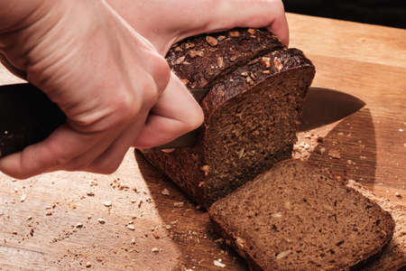 Chef cuts with a knife Whole Fresh fragrant bread on the table. Food concept Wheat pastry on cutting boardの写真素材