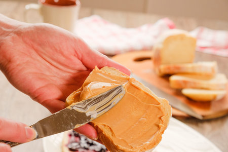 peanut butter sandwich. Cutting board, Kitchen knife and hand.