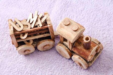 Wooden alphabet letters with toy bulldozer. Educational concept on purple backgroundの写真素材