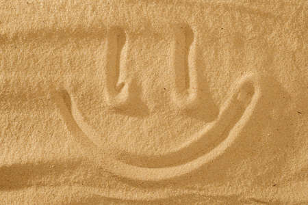 Handwrited face on the sand at the beach, White Sand smile. Symbol smile on beach background.の写真素材