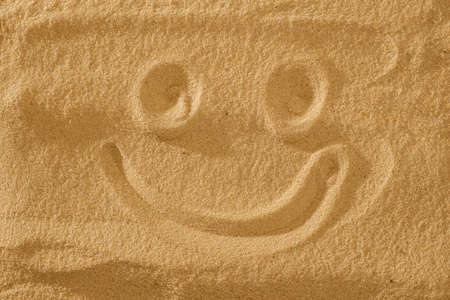 Handwrited face on the sand at the beach, White Sand smile. Symbol smile on beach background.の写真素材
