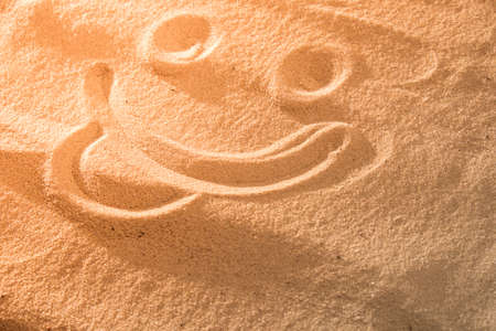 Handwrited face on the sand at the beach, White Sand smile. Symbol smile on beach background.の写真素材
