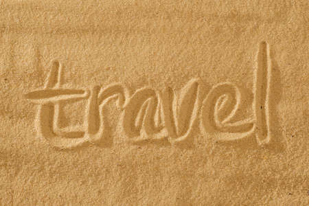 written words travel on sand of beach with wave on backgroundの写真素材