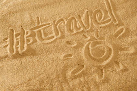 written words travel with sun sign and beam on sand of beach wave on backgroundの写真素材