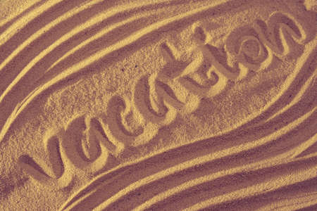Vacation written in the sand on the beach waves in the backgroundの写真素材