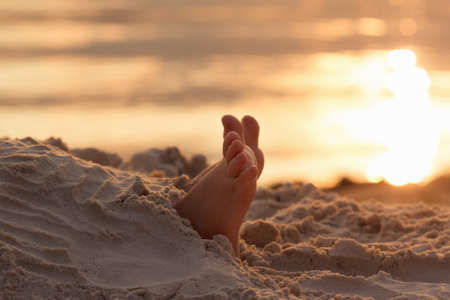 Closeup child kid feet on white sand beach. Sea on background, concept of a relaxing holiday on the coastの写真素材