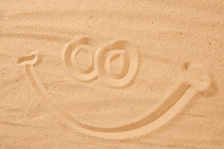 Handwrited face on the sand at the beach, White Sand smile. Symbol smile on beach background.の写真素材