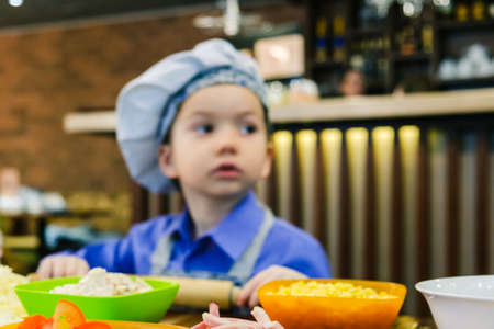 Boy with chef hat preparing the italian pizza in pizzeria bar restaurant. Dough kneading and stretchingの写真素材