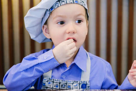 A small cook is trying something food against cafe backgroundの写真素材