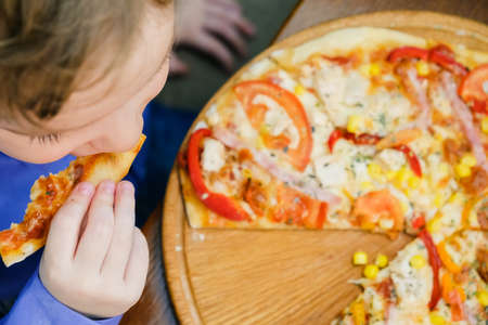 Sweet adorable child, boy, eating pizza at a restaurant, summertime. Top view, overheadの写真素材