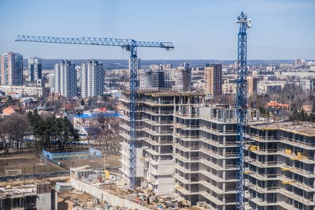 tower cranes against the blue sky. House under construction. Industrial skyline
