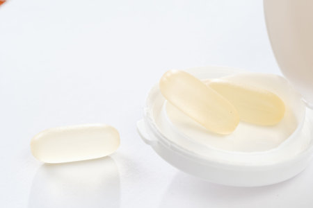 Heap of tablets medicine lying beside of plastic bottle. Pills and bottles are white. Isolated on...