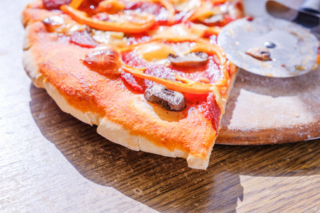 Cutting pepperoni pizza on slices with special knife.の写真素材