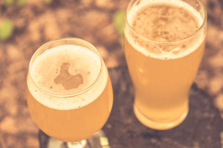 Two glass of cold beer on nature tree park background in forestの写真素材