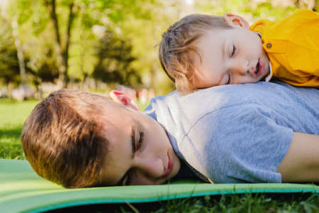 Cheerful two brothers sleep lie on the grass in the parkの写真素材