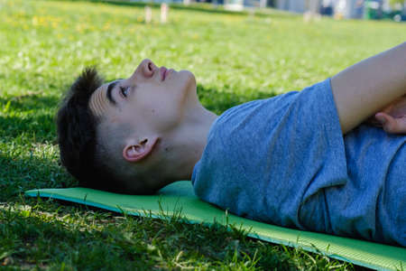 Young teen boy man lying on a grass lawn in parkの写真素材