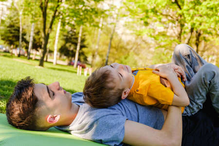 Cheerful two brothers lie on the grass in the park and play in funny games smilingの写真素材