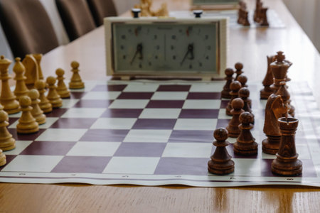 Chess board with pieces and clock on wooden desk In connection with the chess tournament,...