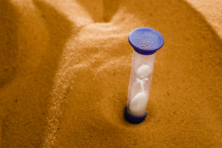 Hourglass on a sand dune beach. concept passage of time vintage style