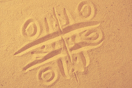 tic-tac-toe drawing in sand background. Game on a beachの写真素材
