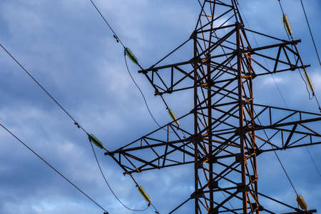 High voltage power pylons against blue sky and sun raysの写真素材
