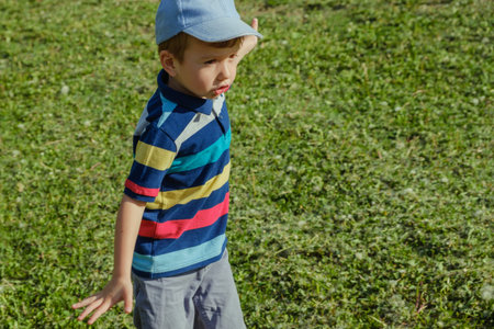 Young boy runs in a green field. Cute child running across park outdoors grass, smiling.